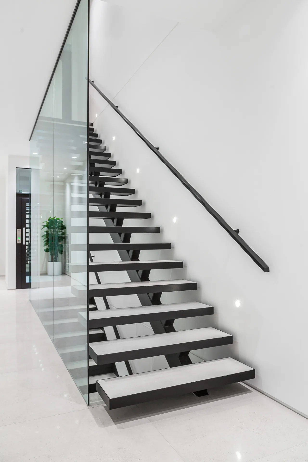 Black steel staircase with glass balustrade in a double-height void