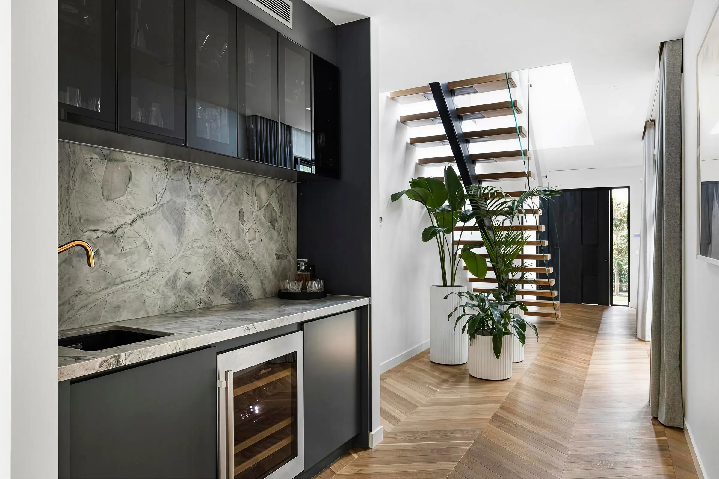 Dark joinery kitchen with herringbone timber floor and stone splashback