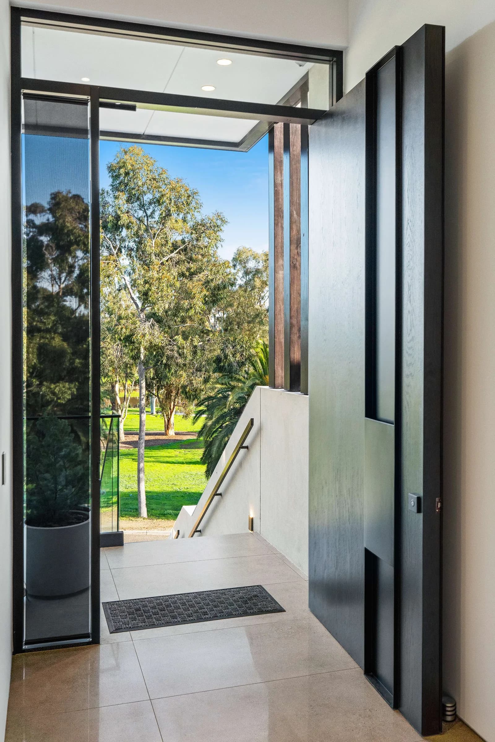 Black steel pivot door opening to the park