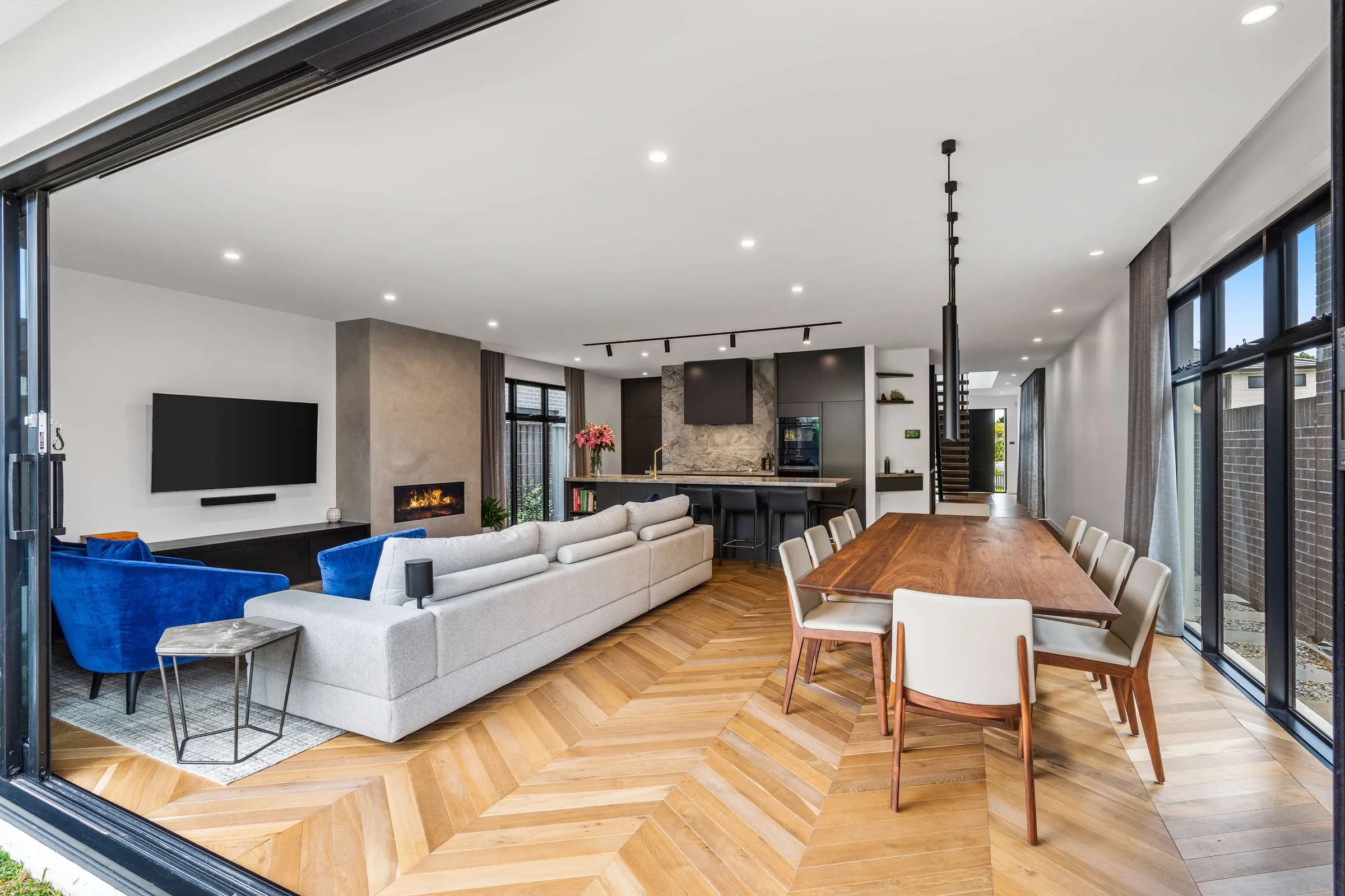Open living and dining room with herringbone floor and walnut table