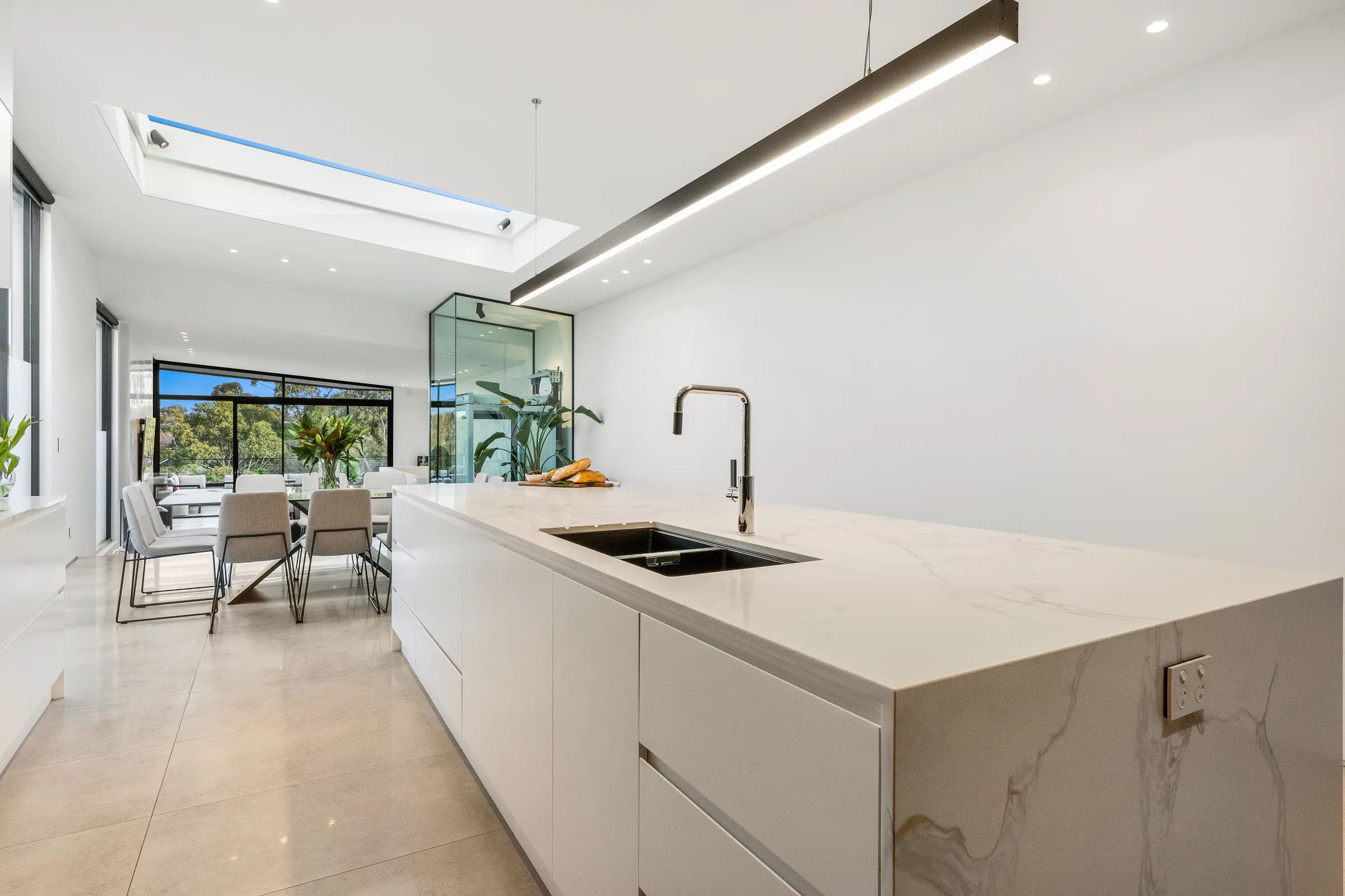 White kitchen with long island bench under a full-length skylight