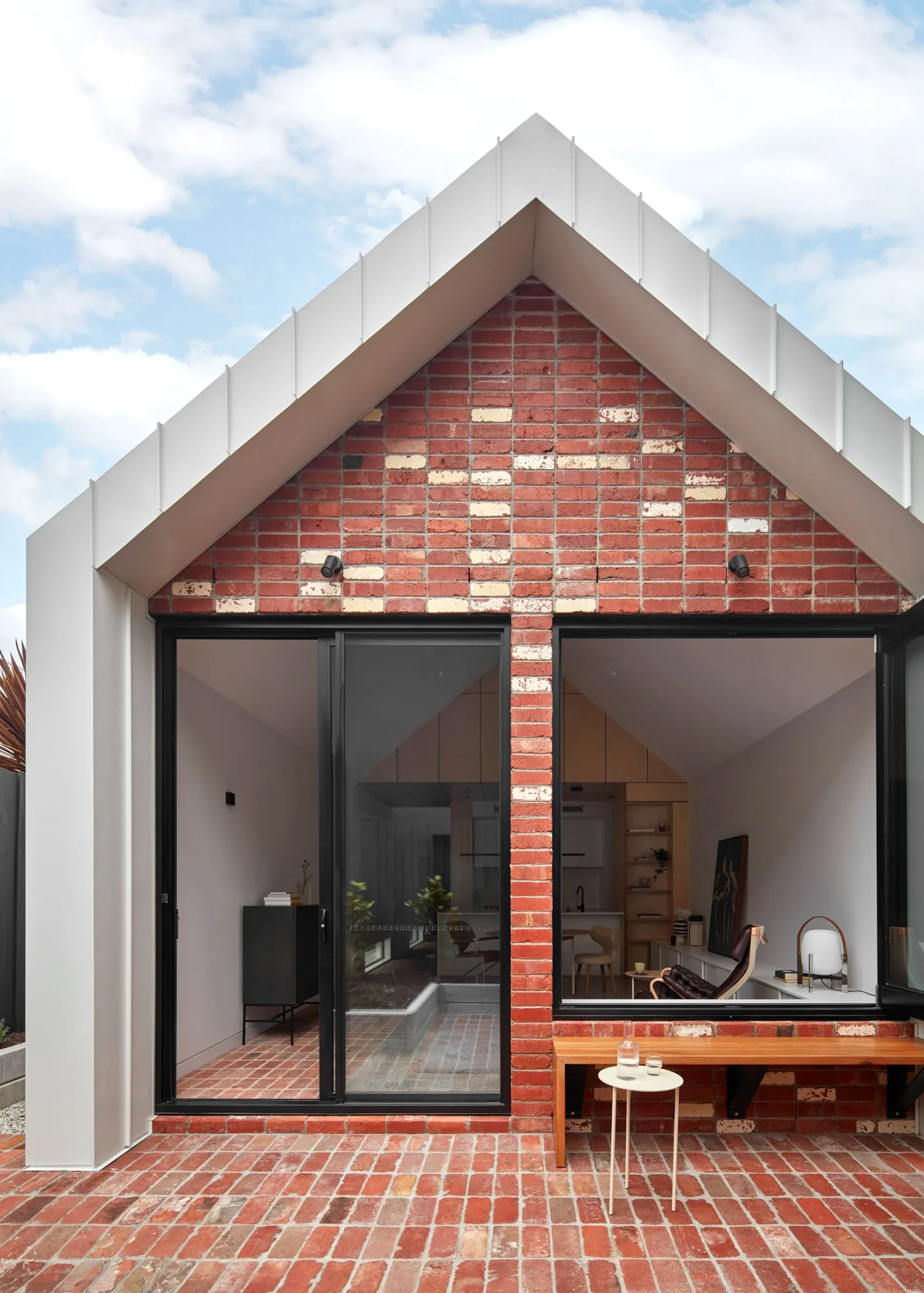 Gabled red brick extension with full-height glazing and original chimney behind
