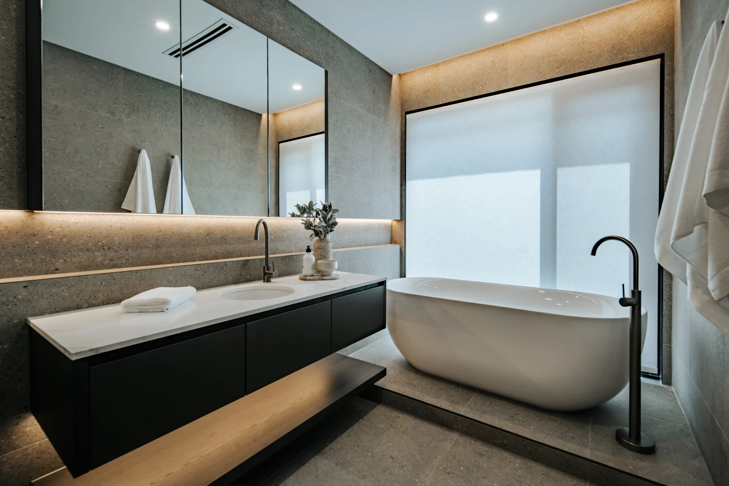 Stone bathroom with floating vanity and freestanding bath