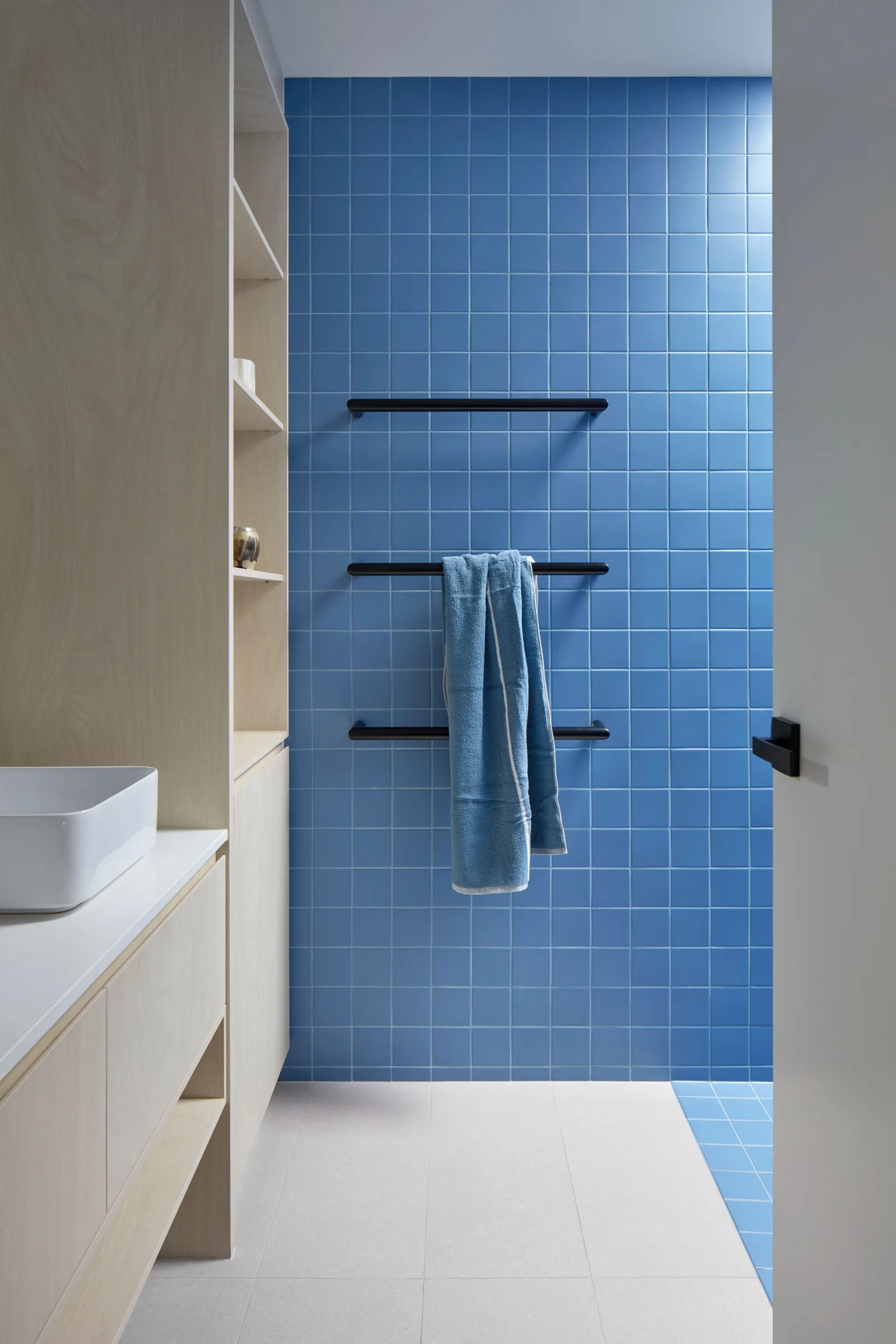 Blue tiled ensuite with towel rail and white basin