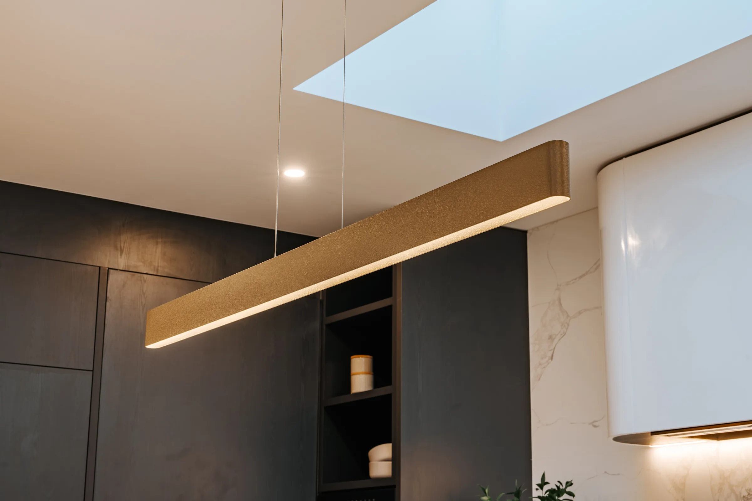 Dark joinery kitchen lit by a full-length ridge skylight