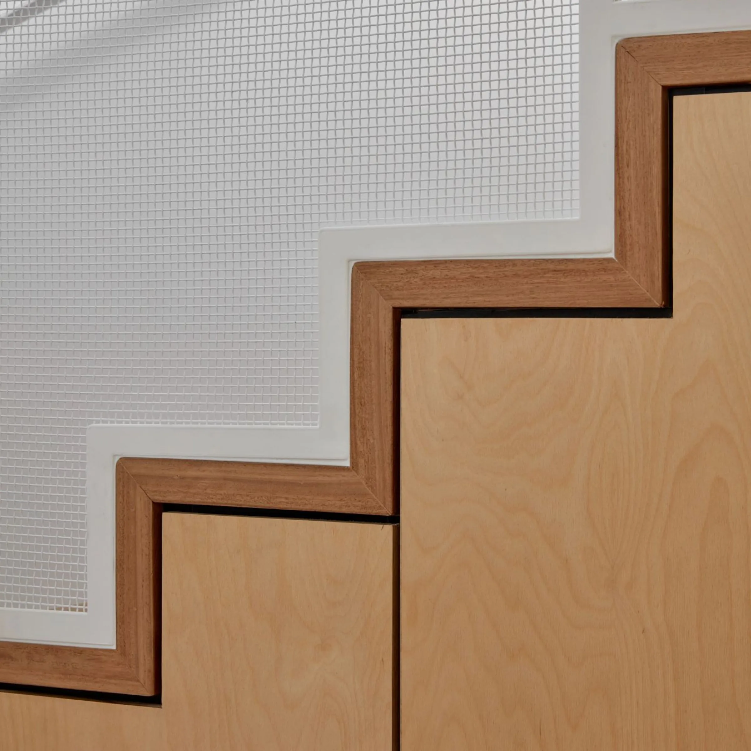 Detail of plywood stair treads against white perforated screen