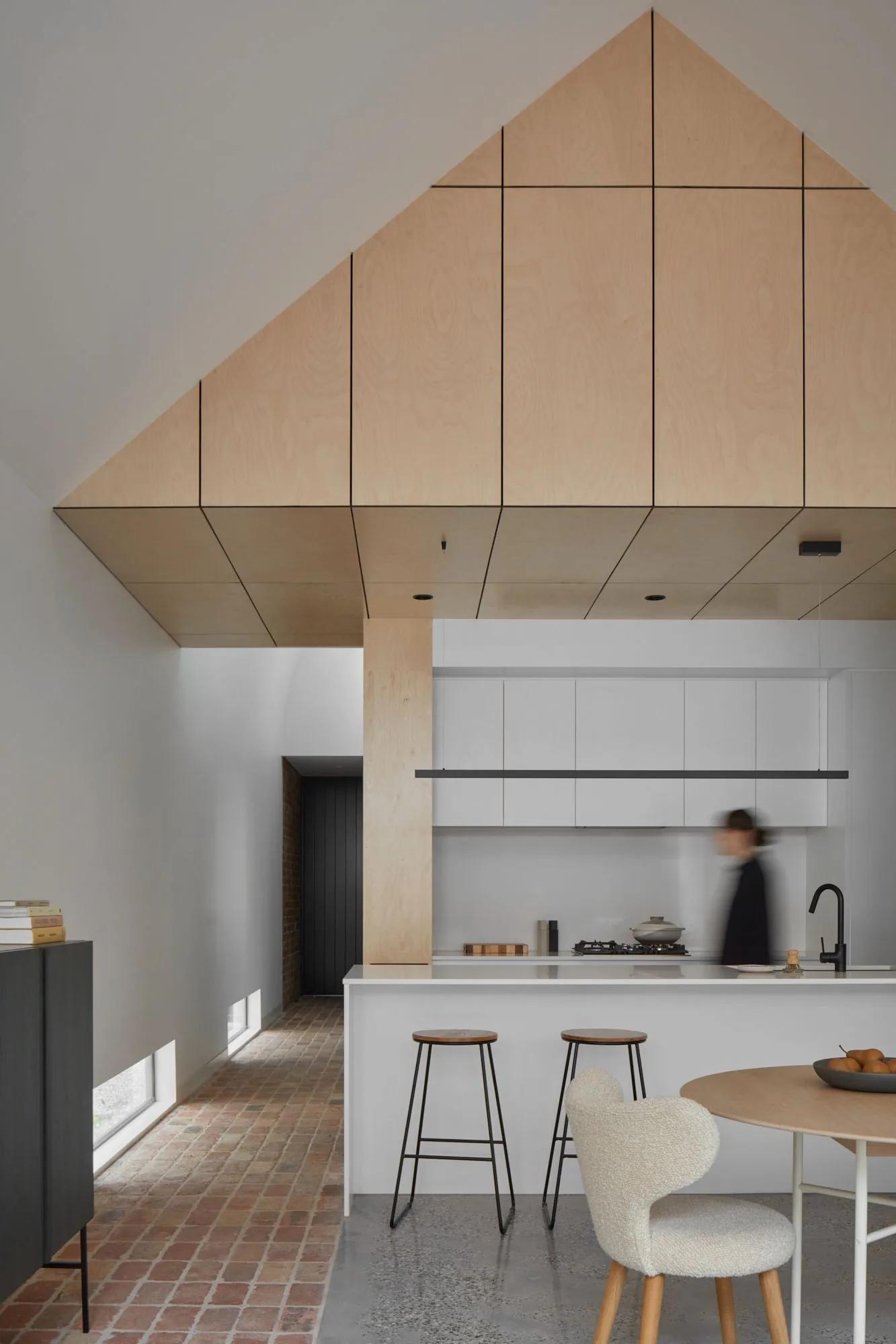 Plywood-lined kitchen nook under the gable with white benchtop